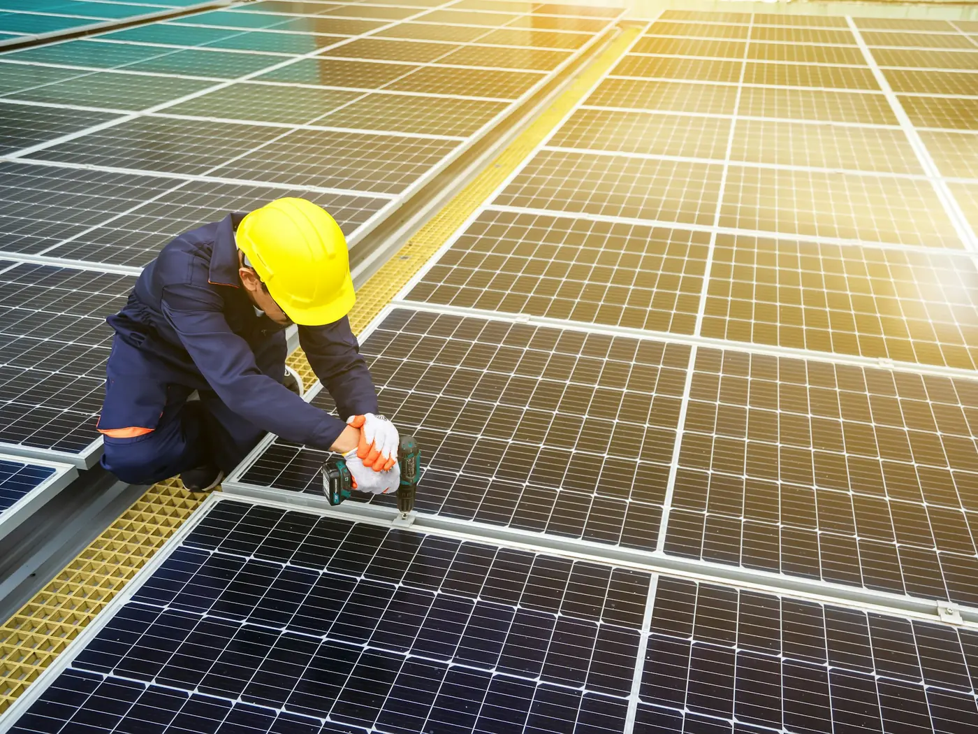Technicien casqué fixant un panneau photovoltaïque sur une toiture ensoleillée
