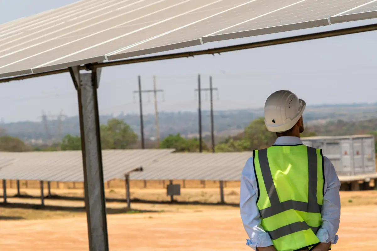 Technicien en gilet de sécurité devant un champ de panneaux photovoltaïques